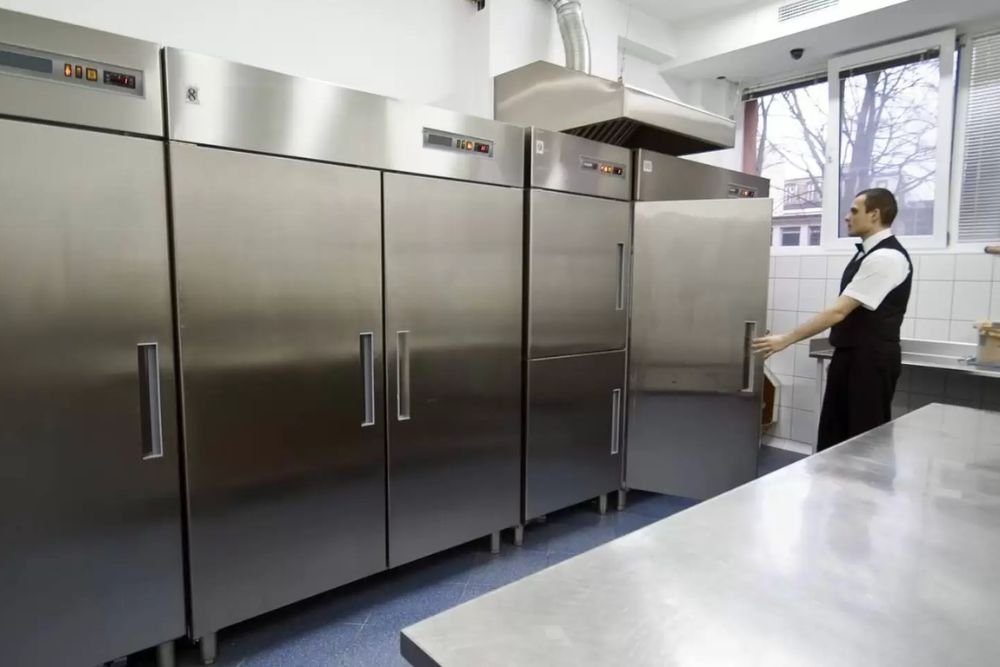 A man is positioned in front of a large stainless steel refrigerator, showcasing a commercial appliance repair service in Reno, NV.