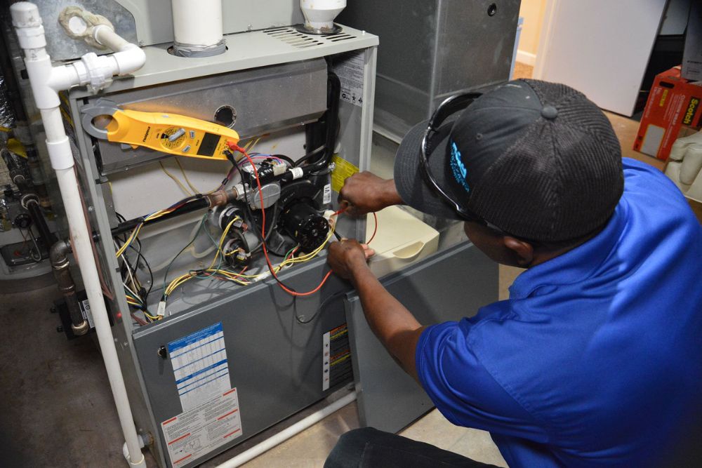 A technician is fixing a furnace in a residence, illustrating heating and air conditioning services in Reno, NV.